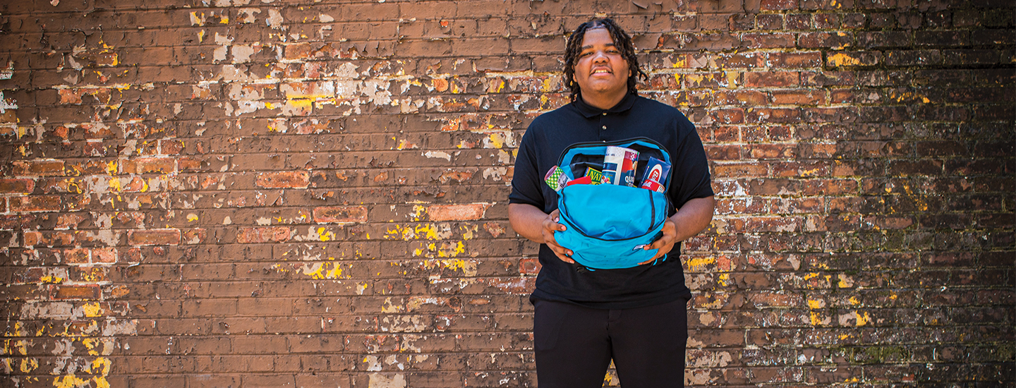 a teen holding a backpack full of food